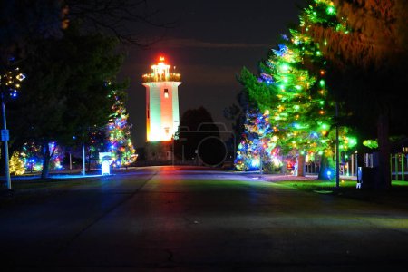 Photo for Fond du Lac, Wisconsin Lighthouse at Lakeside park glows up at night with Christmas colors and Christmas lights. - Royalty Free Image