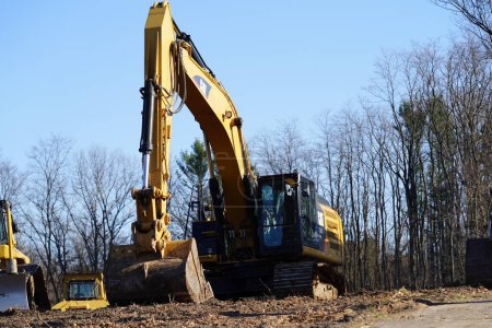 Foto de Una gran excavadora se encuentra en una pila de un sitio de construcción en un día de verano en el bosque. - Imagen libre de derechos