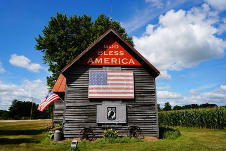 Photo for Green Lake, WIsconsin / USA - May 16th, 2020: Vintage old abandoned wooden log house sits out on the countryside of Green Lake, Wisconsin promoting God Bless America. - Royalty Free Image
