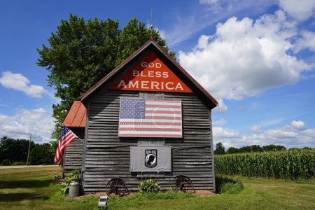 Foto de Green Lake, Washington, Estados Unidos - 16 de mayo de 2020: La antigua casa de madera abandonada se encuentra en el campo de Green Lake, Wisconsin, promoviendo Dios bendiga a América. - Imagen libre de derechos