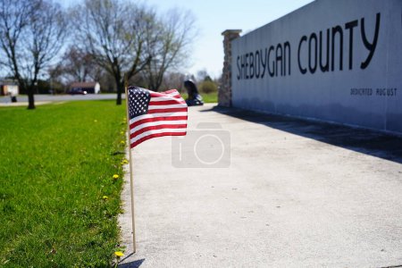 Photo for Little American flag waves in the wind showing pride and remembrance for the fallen veterans at Sheboygan county veteran memorial site. - Royalty Free Image