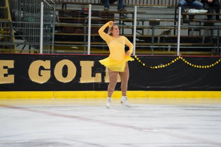 Photo for Mosinee, Wisconsin USA - February 26th, 2021: Young teenager female in a beautiful yellow dress participated in badger state winter games ice skating competition - Royalty Free Image