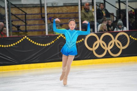 Photo for Mosinee, Wisconsin USA - February 26th, 2021: Young Asian female in a beautiful blue dress participated in badger state winter games ice skating competition - Royalty Free Image