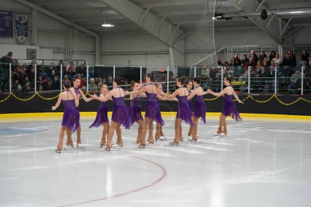 Foto de Mosinee, Wisconsin, Estados Unidos - 26 de febrero de 2021: Mujeres jóvenes adultas en hermosos vestidos púrpura patinando juntas en la competición de patinaje sobre hielo de los juegos de invierno de Badger State - Imagen libre de derechos