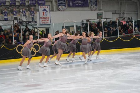 Téléchargez les photos : Mosinee, Wisconsin États-Unis - 26 février 2021 : Jeunes femmes en belles robes sombres synchronisées patinant ensemble dans l'état du blaireau Jeux d'hiver compétition de patinage sur glace. - en image libre de droit