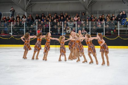 Foto de Mosinee, Wisconsin, Estados Unidos - 26 de febrero de 2021: Mujeres jóvenes en hermosos vestidos de colores sincronizados patinando juntas en la competencia de patinaje sobre hielo de los juegos de invierno de Badger State. - Imagen libre de derechos