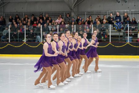 Téléchargez les photos : Mosinee, Wisconsin États-Unis - février 26th, 2021 : Jeunes femmes adultes en belles robes violettes synchronisées patinant ensemble dans la compétition de patinage sur glace des jeux d'hiver de l'État du blaireau - en image libre de droit