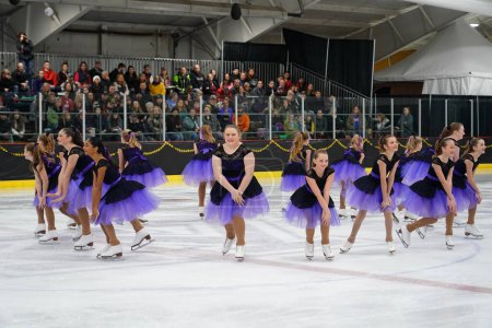Photo for Mosinee, Wisconsin USA - February 26th, 2021: Young females in beautiful purple dresses synchronized skating together in the badger state winter games ice skating competition. - Royalty Free Image