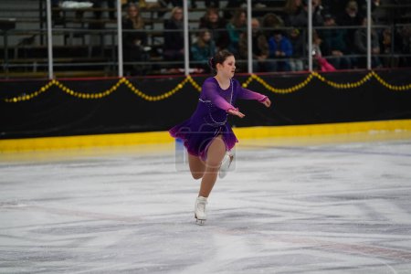 Foto de Mosinee, Wisconsin, EE.UU. - 26 de febrero de 2021: Joven adolescente caucásica con un hermoso vestido morado participó en la competencia de patinaje sobre hielo de los juegos de invierno de Badger State. - Imagen libre de derechos