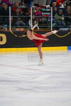 Photo for Mosinee, Wisconsin USA - February 26th, 2021: Young adult female in a beautiful red dress participated in badger state winter games ice skating competition - Royalty Free Image