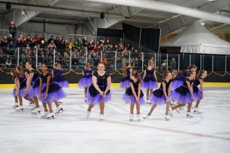 Téléchargez les photos : Mosinee, Wisconsin États-Unis - 26 février 2021 : Jeunes femmes en belles robes violettes synchronisées patinant ensemble dans la compétition de patinage sur glace des jeux d'hiver de l'État du blaireau. - en image libre de droit