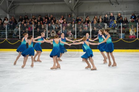 Téléchargez les photos : Mosinee, Wisconsin États-Unis - 26 février 2021 : Jeunes femmes en belles robes bleues patinant ensemble dans la compétition de patinage sur glace des jeux d'hiver de l'État du blaireau - en image libre de droit