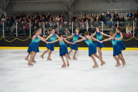Foto de Mosinee, Wisconsin, Estados Unidos - 26 de febrero de 2021: Mujeres jóvenes en hermosos vestidos azules patinando juntas en la competencia de patinaje sobre hielo de los juegos de invierno de Badger State - Imagen libre de derechos