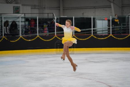 Téléchargez les photos : Mosinee, Wisconsin États-Unis - 26 février 2021 : Une jeune femme adulte dans une belle robe jaune a participé à la compétition de patinage sur glace des jeux d'hiver de l'État du blaireau - en image libre de droit