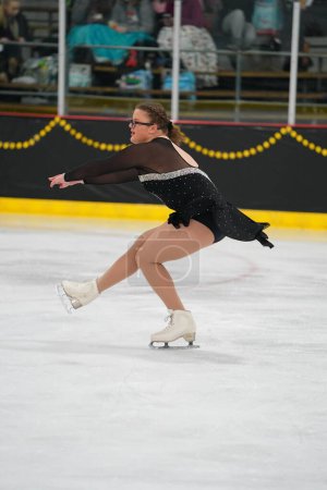 Photo for Mosinee, Wisconsin USA - February 26th, 2021: Young teenager female in a beautiful black dress participated in badger state winter games ice skating competition - Royalty Free Image