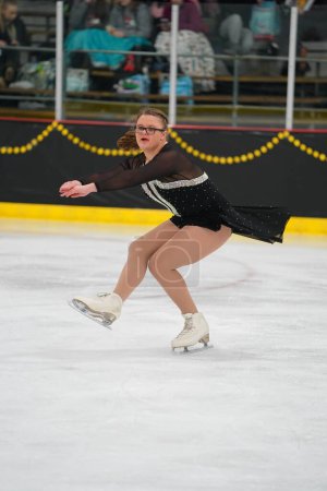 Foto de Mosinee, Wisconsin, Estados Unidos - 26 de febrero de 2021: Una joven adolescente con un hermoso vestido negro participó en la competencia de patinaje sobre hielo de los juegos de invierno de Badger State. - Imagen libre de derechos