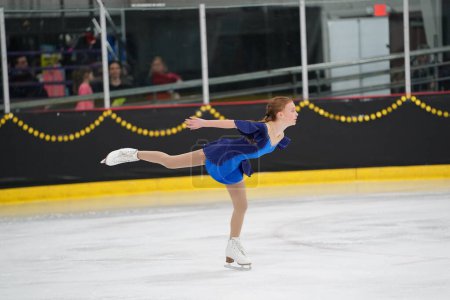 Photo for Mosinee, Wisconsin USA - February 26th, 2021: Young Asian female in a beautiful blue dress participated in badger state winter games ice skating competition - Royalty Free Image