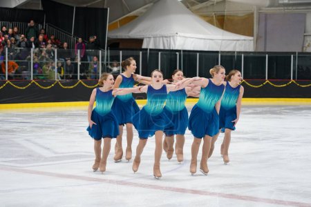 Téléchargez les photos : Mosinee, Wisconsin États-Unis - 26 février 2021 : Jeunes femmes en belles robes bleues synchronisées patinant ensemble dans la compétition de patinage sur glace des jeux d'hiver de l'État du blaireau. - en image libre de droit