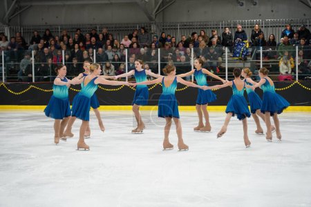 Photo for Mosinee, Wisconsin USA - February 26th, 2021: Young females in beautiful blue dresses synchronized skating together in the badger state winter games ice skating competition. - Royalty Free Image