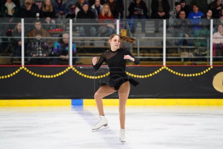 Téléchargez les photos : Mosinee, Wisconsin États-Unis - février 26th, 2021 : Jeune adolescente dans une belle robe noire a participé à la compétition de patinage sur glace des jeux d'hiver de l'État du blaireau - en image libre de droit