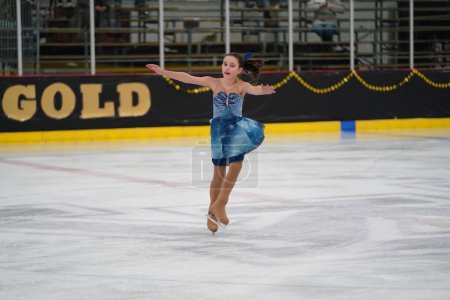 Photo for Mosinee, Wisconsin USA - February 26th, 2021: Young adult female in a beautiful blue dress participated in badger state winter games ice skating competition. - Royalty Free Image