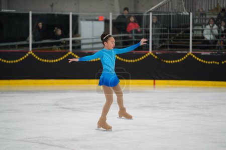 Photo for Mosinee, Wisconsin USA - February 26th, 2021: Young Asian female in a beautiful blue dress participated in badger state winter games ice skating competition. - Royalty Free Image