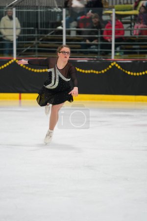 Téléchargez les photos : Mosinee, Wisconsin États-Unis - février 26th, 2021 : Jeune adolescente dans une belle robe noire a participé à la compétition de patinage sur glace des jeux d'hiver de l'État du blaireau - en image libre de droit