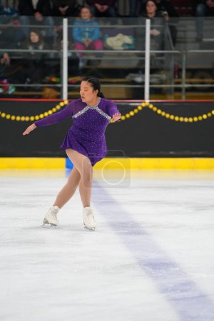 Téléchargez les photos : Mosinee, Wisconsin États-Unis - février 26th, 2021 : Femme adulte asiatique dans une belle robe pourpre a participé à la compétition de patinage sur glace des jeux d'hiver de l'État du blaireau - en image libre de droit