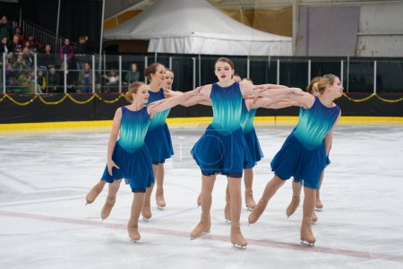 Foto de Mosinee, Wisconsin, Estados Unidos - 26 de febrero de 2021: Mujeres jóvenes en hermosos vestidos azules, patinando juntas en la competición de patinaje sobre hielo de los juegos de invierno de Badger State. - Imagen libre de derechos