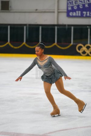 Photo for Mosinee, Wisconsin USA - February 26th, 2021: Adult african american female in a beautiful grey dress participated in badger state winter games ice skating competition - Royalty Free Image