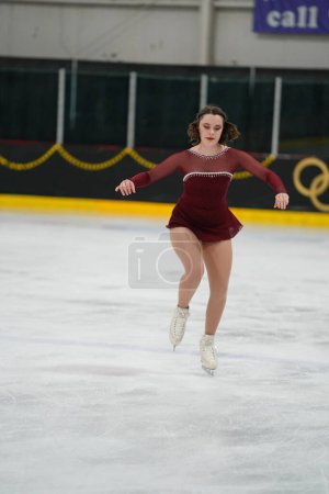 Photo for Mosinee, Wisconsin USA - February 26th, 2021: Young adult female in a beautiful red dress participated in badger state winter games ice skating competition. - Royalty Free Image
