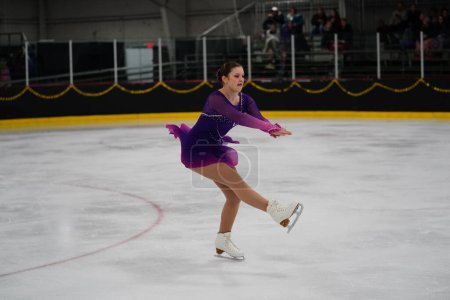 Foto de Mosinee, Wisconsin, EE.UU. - 26 de febrero de 2021: Una joven adulta con un hermoso vestido morado participó en la competencia de patinaje sobre hielo de los juegos de invierno de Badger State.. - Imagen libre de derechos