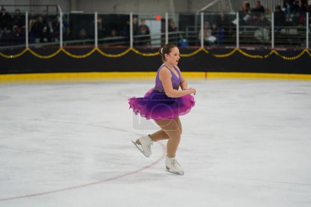 Photo for Mosinee, Wisconsin USA - February 26th, 2021: Young caucasian teenager female in a beautiful purple dress participated in badger state winter games ice skating competition - Royalty Free Image