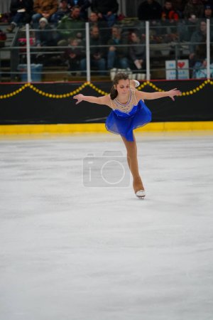 Photo for Mosinee, Wisconsin USA - February 26th, 2021: Young adult female in a beautiful blue dress participated in badger state winter games ice skating competition - Royalty Free Image