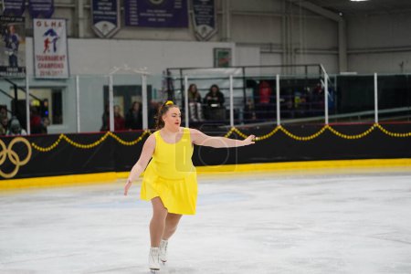 Téléchargez les photos : Mosinee, Wisconsin États-Unis - 26 février 2021 : Jeune adolescente dans une belle robe jaune a participé à la compétition de patinage sur glace des jeux d'hiver de l'État du blaireau - en image libre de droit