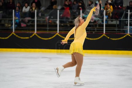 Photo for Mosinee, Wisconsin USA - February 26th, 2021: Adult female in a beautiful yellow dress participated in badger state winter games ice skating competition - Royalty Free Image