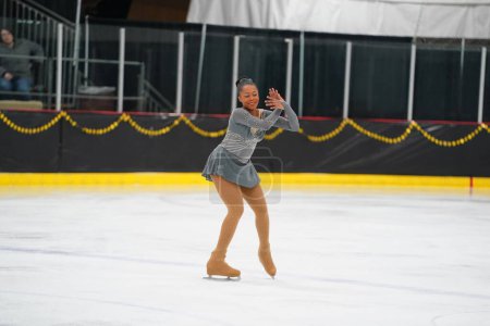 Foto de Mosinee, Wisconsin, EE.UU. - 26 de febrero de 2021: Mujer afroamericana adulta con un hermoso vestido gris participó en la competencia de patinaje sobre hielo de los juegos de invierno de Badger State. - Imagen libre de derechos