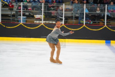 Foto de Mosinee, Wisconsin, EE.UU. - 26 de febrero de 2021: Mujer afroamericana adulta con un hermoso vestido gris participó en la competencia de patinaje sobre hielo de los juegos de invierno de Badger State.. - Imagen libre de derechos