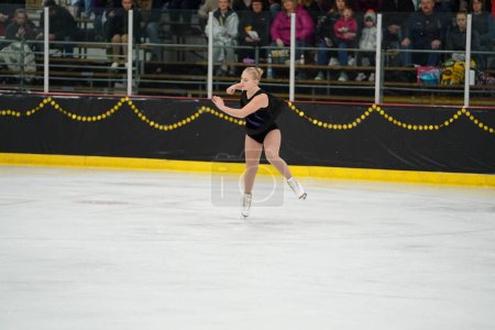 Foto de Mosinee, Wisconsin, EE.UU. - 26 de febrero de 2021: Mujer adulta con un hermoso vestido negro participó en la competencia de patinaje sobre hielo de los juegos de invierno de Badger State. - Imagen libre de derechos