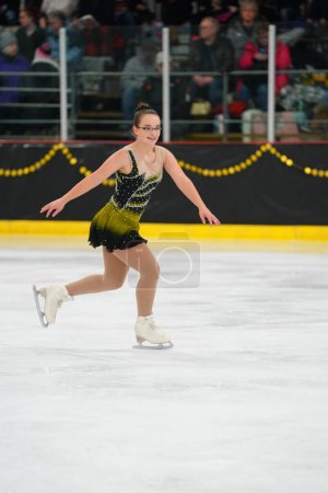 Foto de Mosinee, Wisconsin, EE.UU. - 26 de febrero de 2021: Mujer adulta con un hermoso vestido negro participó en la competencia de patinaje sobre hielo de los juegos de invierno de Badger State. - Imagen libre de derechos