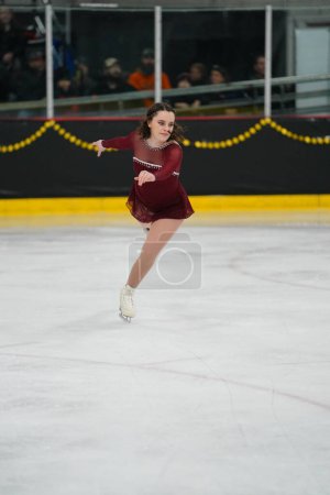 Photo for Mosinee, Wisconsin USA - February 26th, 2021: Adult female in a beautiful red dress participated in badger state winter games ice skating competition - Royalty Free Image