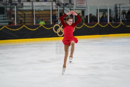 Photo for Mosinee, Wisconsin USA - February 26th, 2021: Young adult female in a beautiful red dress participated in badger state winter games ice skating competition - Royalty Free Image
