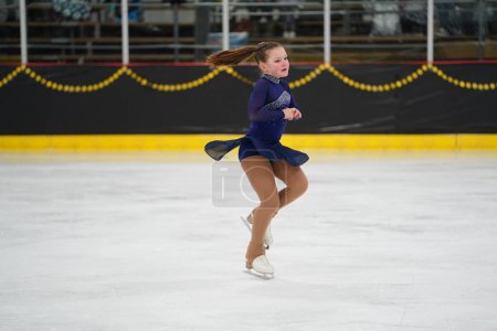 Foto de Mosinee, Wisconsin, EE.UU. - 26 de febrero de 2021: Una joven adulta con un hermoso vestido morado participó en la competencia de patinaje sobre hielo de los juegos de invierno de Badger State. - Imagen libre de derechos