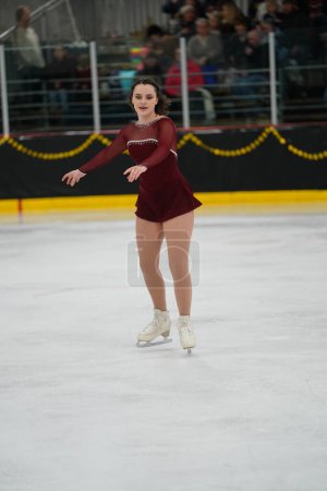 Téléchargez les photos : Mosinee, Wisconsin États-Unis - 26 février 2021 : Une jeune femme adulte dans une belle robe rouge a participé à la compétition de patinage sur glace des jeux d'hiver de l'État du blaireau. - en image libre de droit