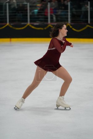 Photo for Mosinee, Wisconsin USA - February 26th, 2021: Young adult female in a beautiful red dress participated in badger state winter games ice skating competition. - Royalty Free Image