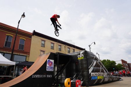 Photo for Racine, Wisconsin USA - September 16th, 2023: Bicycle stuntmen on BMX bikes doing stunts on half-pipe ramps for a crowd of people in the streets of Racine, Wisconsin - Royalty Free Image