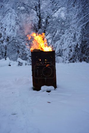 Foto de El barril de basura en llamas se sienta afuera durante el frío invierno. - Imagen libre de derechos
