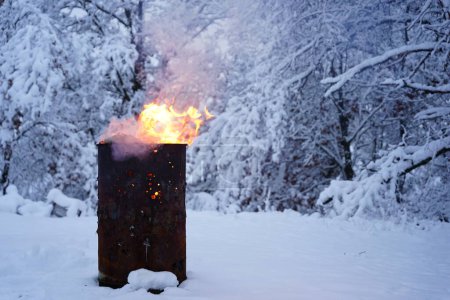 Téléchargez les photos : Baril de déchets brûlant se trouve à l'extérieur pendant le froid de l'hiver. - en image libre de droit