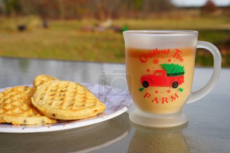 Photo for Glass Christmas coffee mug with coffee and creamer alongside a plate of chocolate chip waffles. - Royalty Free Image