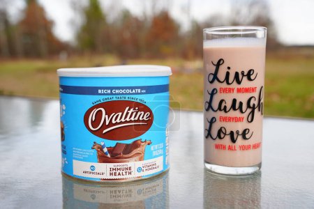Foto de Nueva Lisboa, Wisconsin, EE. UU. - 8 de noviembre de 2022: Una lata de Nestl Ovaltine rica mezcla de leche de chocolate y un vaso de leche se sientan afuera. - Imagen libre de derechos
